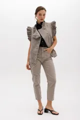 Jean gris lavado, estilo mom fit, con aplique fruncido en forma de espiral en la pierna izquierda, tiro alto, bolsillos delanteros y traseros funcionales, y cierre frontal con botón y cremallera.