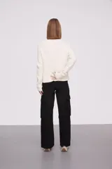 Sweater blanco de manga larga con diseño texturizado y detalles brillantes.