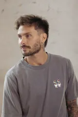 Remera gris con cuello redondo y mangas cortas. Estampado pequeño de dos patos en el pecho.
