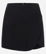 Short pollera negro de sastrería, corte corto, con diseño de traspaso redondeado en el frente y cierre de cremallera en la espalda.