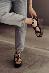 Sandalias negras de plataforma con tiras de gamuza y esferas doradas decorativas.