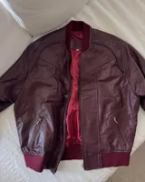 Campera bomber de cuero color bordó con forro interior rojo, cuello, puños y cintura acanalados.