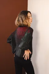 Cárdigan tejido con lurex, con cuello redondo, manga 3/4 y cierre frontal con botones forrados. Diseño con rayas verticales en tonos verde, azul y violeta sobre fondo negro con brillo.