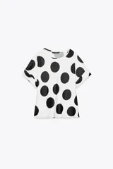 Top blanco con lunares negros grandes, cuello redondo y mangas cortas.