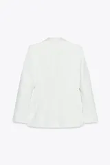 Blazer blanca entallada con cuello solapa combinado, manga larga con hombreras, bolsillos de plastrón en delantero, costuras marcadas, forro interior a tono y cierre frontal con botón forrado.
