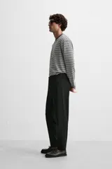 Pantalón slim fit negro confeccionado en tejido con elasticidad en ambas direcciones. Cuenta con bolsillos frontales y traseros de vivo con botón. Cierre frontal con cremallera y botón.