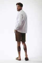 Camisa celeste a rayas verticales blancas, de corte clásico, manga larga y cuello abotonado.