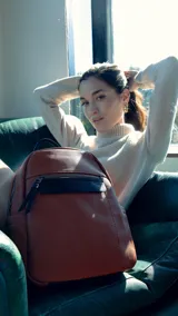 Mochila negra de símil cuero con bolsillo frontal con cierre. En su interior tiene dos bolsillos con cierre y uno abierto con división. Tiene asa de mano y correas regulables.