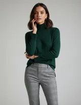 Polera de punto fino marca Nienty, color blanco, con cuello alto volcado y mangas largas con detalle de tajo en los puños.