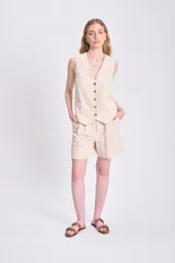 Short color crema de lino twill, de tiro alto con pinzas en la cintura, bolsillos laterales y cierre frontal con botón.
