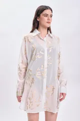 Camisa blanca de algodón con estampado de ramas doradas, de corte recto y mangas largas.