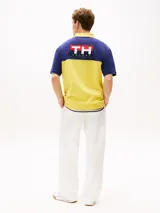 Chomba Tommy Hilfiger de corte amplio, con diseño color block en azul y amarillo, cuello clásico, cartera de tres botones, logo bordado en el pecho y logo oversize en la espalda.