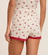 Short de pijama de viscosa color crema con rayas finas oscuras y estampado de cerezas rojas. Presenta ribetes de encaje rojo en los bordes de las piernas y cintura.