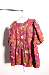 Blusa de calce holgado con estampado floral en tonos marrones, fucsias, naranjas y blancos. Escote en V con doble lazo ajustable y mangas 3/4 con volumen.