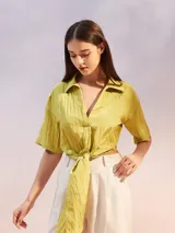 Camisa color verde lima con textura arrugada, corte holgado, mangas cortas y lazo para atar en la parte delantera.