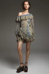 Vestido corto con estampado paisley en tonos ocre, azul y marrón. Tiene escote recto con volantes, mangas largas abullonadas con puños elásticos y cintura elástica.