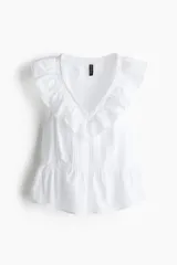 Blusa blanca sin mangas de tejido liviano de algodón con alforzas e inserciones de encaje, escote en V con ribete de volados y peplum con leve vuelo.