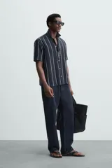 Camisa de hombre a rayas verticales color beige y blanco, de corte relaxed fit, manga corta y cuello bowling.