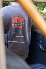 Buzo marrón con estampa de hamburguesa andando en skate y la frase "skateboarding hamburger".