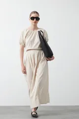 Top negro de manga corta con escote redondo y frunces en la costura de la sisa, creando un efecto de manga abullonada. El tejido parece ligero y con textura.