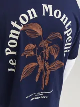 Remera azul marino de algodón con cuello redondo y corte holgado. Estampa en la espalda con diseño de planta en color naranja y texto en blanco.