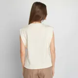 Camiseta blanca sin mangas con cuello redondo y hombreras marcadas.
