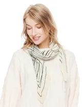 Pañuelo o chal de poliéster color crema con estampado abstracto en líneas negras. Presenta textura plisada.