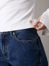 Top blanco de algodón con textura de canalé, corte slim, cuello redondo y mangas largas con puños con abertura.