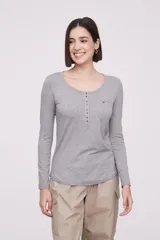 Remera de manga larga entallada en color blanco, confeccionada en algodón. Presenta cuello redondo con una hilera de botones frontales y un pequeño bolsillo en el pecho con detalle de botón.