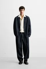 Blazer azul oscuro de denim, corte relaxed fit, con cuello de solapas de muesca, manga larga con puños abotonados, bolsillos de solapa en la cadera, abertura en el centro de la espalda y cierre frontal con botones. Sin forro interior.