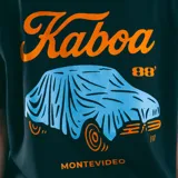 Remera negra de corte recto con estampado en el pecho con la palabra 'Kaboa' en celeste y 'Montevideo' en naranja.