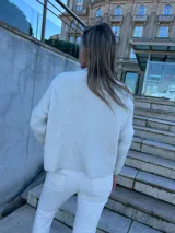 Sweater celeste con mangas blancas, tejido con ochos en la parte delantera y liso en la parte trasera.