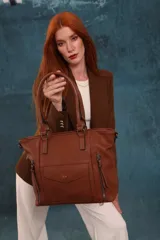 Cartera bandolera de símil cuero color marrón claro, con doble asa rígida y correa regulable. Presenta dos bolsillos frontales con cierre vertical y un bolsillo frontal con solapa y botón. Cuenta con dos divisiones internas.