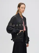 Campera bomber de denim negro con cierre metálico y detalles de diseño en la parte delantera.