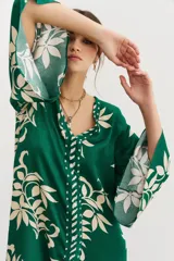 Vestido midi verde con estampado de hojas color crema, escote en V y mangas 3/4 amplias.