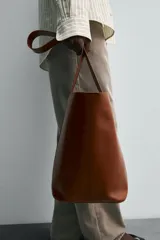 Bolso tipo shopper negro fabricado en piel, con asa de hombro y cierre magnético.