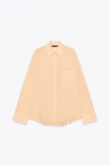 Camisa color durazno confeccionada en algodón, de corte amplio, con cuello solapa, manga larga con puños abotonados, hombros caídos, bolsillo de parche en el pecho, pinzas en la espalda y cierre frontal con botones.