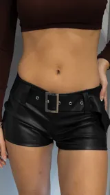 Short negro de cuero sintético con cinturón con hebilla metálica y ojales.