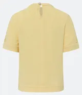 Blusa color amarillo pálido en crepé con cuello redondo, mangas cortas y detalles cutout en el cuello y en las mangas.
