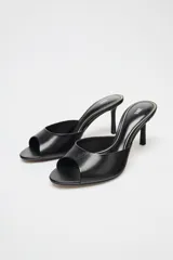 Zapato tipo mule de cuero negro con punta redonda y tacón fino.