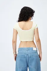 Top corto de punto acanalado color rosa, con silueta ajustada, escote redondo y ribetes blancos en cuello y mangas.