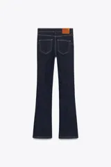 Pantalón de jean azul oscuro, de tiro bajo, corte slim fit y bootcut. Con cinco bolsillos y cierre frontal con cremallera y botón.