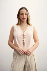 Chaleco color rosa pálido con escote en V y lazos ajustables en el centro.