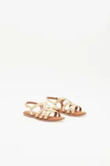 Sandalias bajas doradas con tiras finas cruzadas y hebilla en el tobillo.