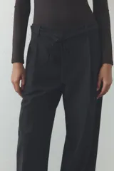 Pantalón negro de tiro alto, corte ancho y largo midi. Incluye bolsillos delanteros, pinzas y cinturón de la misma tela.