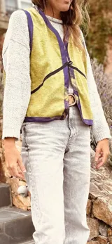 Chaleco color crema con ribete amarillo, de corte recto y sin mangas.