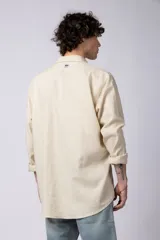 Camisa color arena de lino, manga larga, con cuello clásico y corte holgado.
