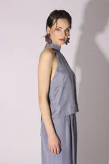 Conjunto de blusa y pantalón color gris azulado de seda, con cuello halter y corte holgado.
