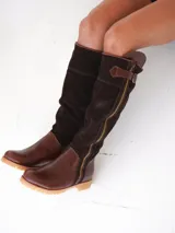 Botas altas de cuero marrón combinadas con gamuza blanca con estampado de vaca, forradas en cuero y con cierre de bronce.