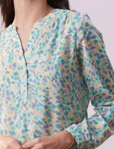 Blusa de gasa estampada con cuello a la base, escote en V y abertura con botones. Tiene mangas largas con largo regulable.